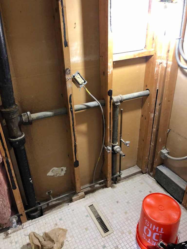 Exposed plumbing inside of a bathroom wall