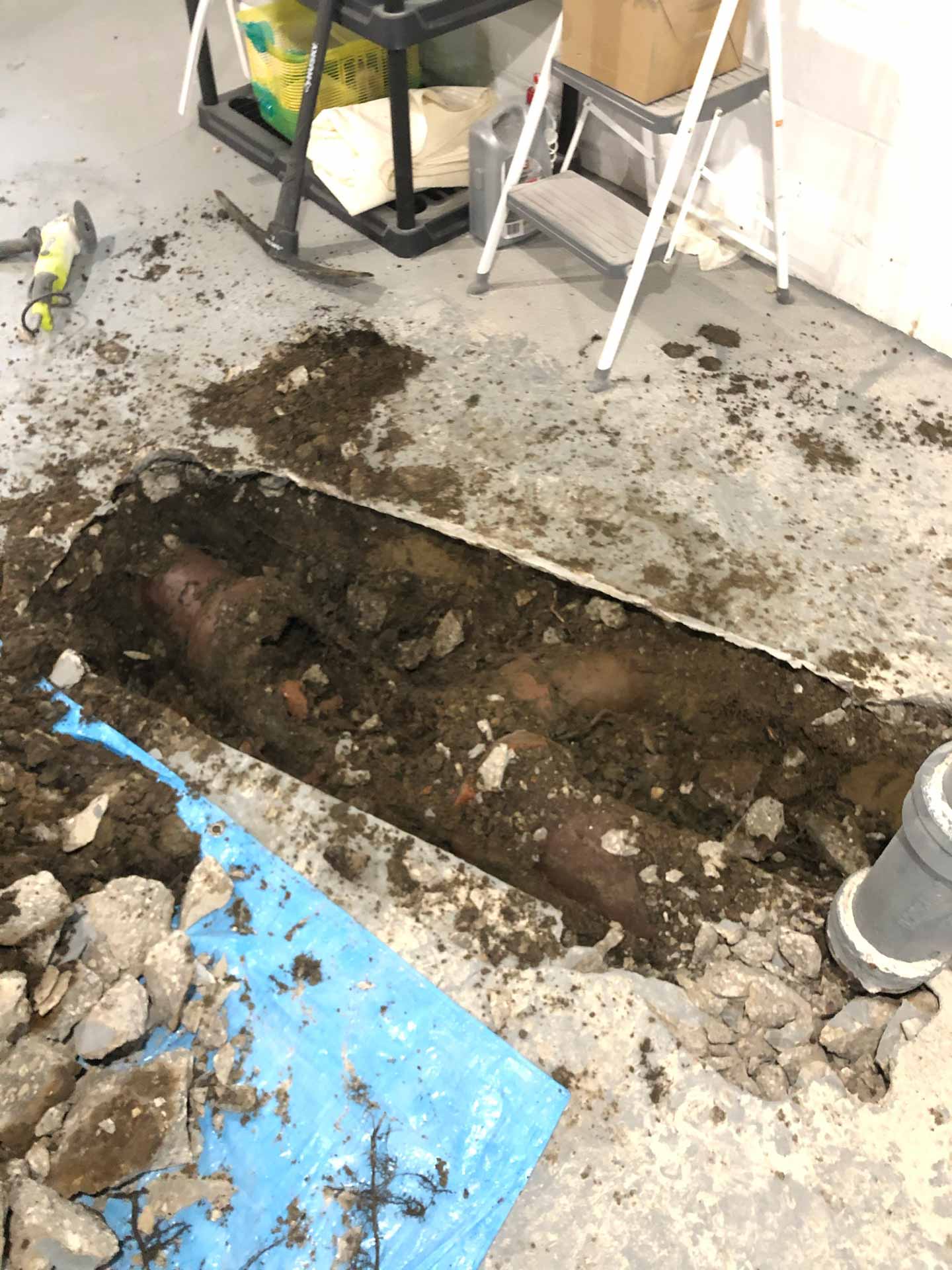 Hole in basement floor showing a burst pipe