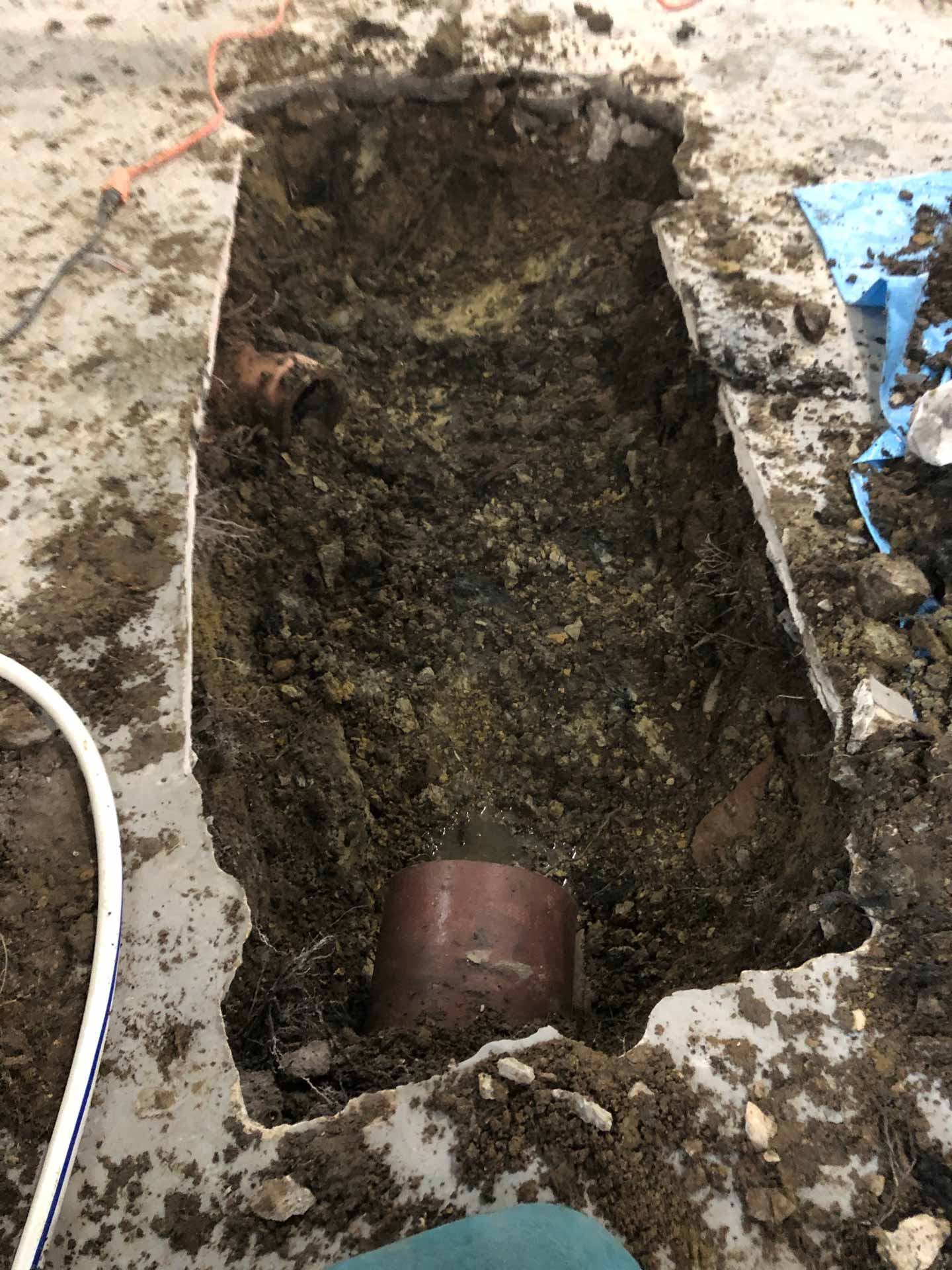 Hole in basement floor showing a burst pipe